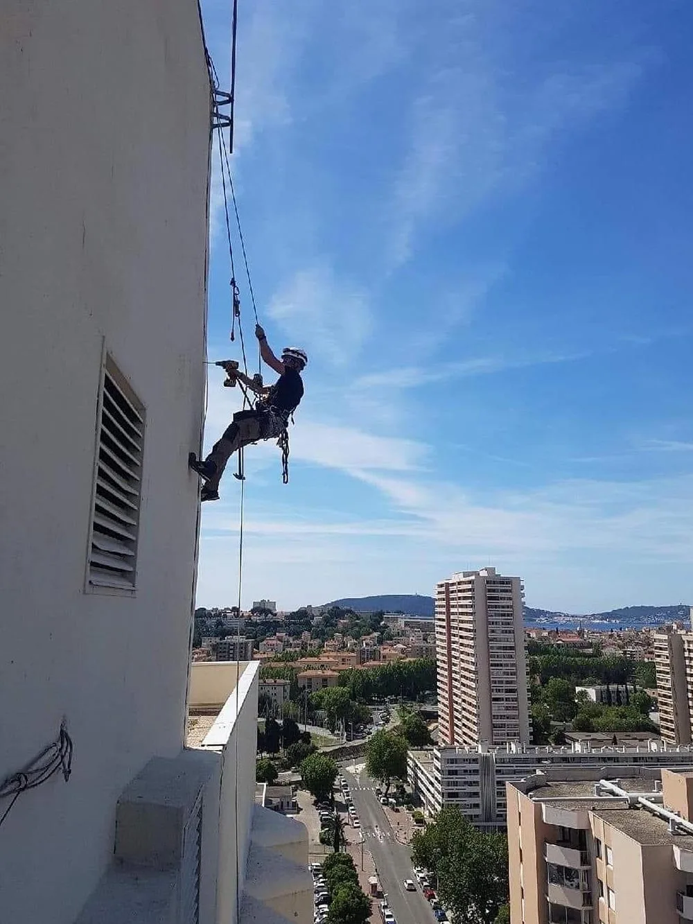 Cordiste perce des trous dans une façade